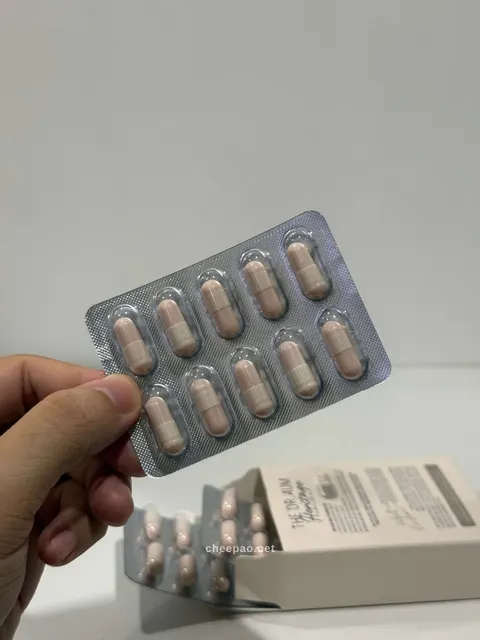 มือถือแผงแคปซูล Dr.Aum Liposomal Vitamin C+ สีชมพูสลับขาว 10 เม็ด ด้านหลังเป็นกล่องที่เปิดออก