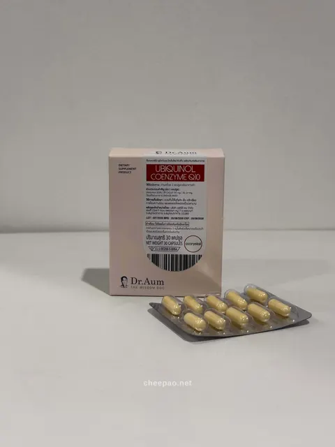 กล่อง Dr.Aum Ubiquinol Coenzyme Q10 สีชมพูอ่อนฉลากแดง ตั้งบนโต๊ะสีขาว ข้างหน้ามีแผงแคปซูลสีเหลือง 10 เม็ด